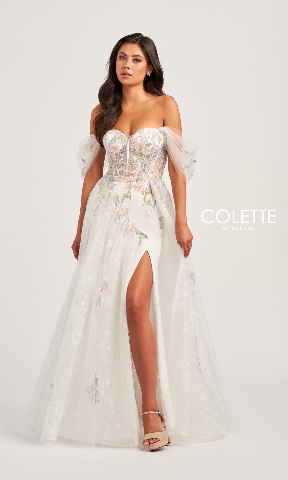 A woman models the Colette Off-the-Shoulder Lace Prom Dress CL5169, featuring white lace, sheer puff sleeves, floral embroidery, and a thigh-high slit.